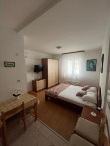 a small bedroom with a bed and a table at Apartmani Vinko Palaversić in Jelsa