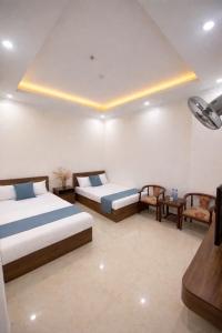 a hotel room with two beds and a tv at Hiếu Thảo Hotel & Restaurant in Lôc Hải