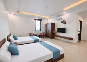 a hotel room with two beds and a television at Hiếu Thảo Hotel & Restaurant in Lôc Hải