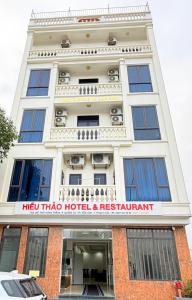 a white building with a red trivia hotel and restaurant at Hiếu Thảo Hotel & Restaurant in Lôc Hải