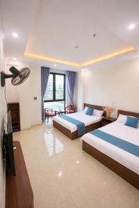 a hotel room with two beds and a television at Hiếu Thảo Hotel & Restaurant in Lôc Hải