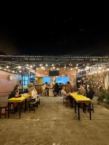 a group of people sitting at tables at a restaurant at night at Cheese Hostel Manila in Manila
