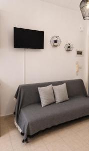 a couch with two pillows and a television on a wall at University Apartment in Heraklio +1 photo