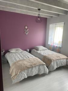 a bedroom with two beds and a purple wall at La Salamandre in Valprivas
