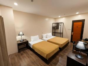 a hotel room with two beds and a desk at Top Star Hotel Manaoag in Manaoag