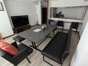a living room with a table and chairs and a television at Kvillage BLDG 無料駐車場付き 原爆ドームまで徒歩15分 大人数でもOK in Hiroshima