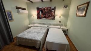 a bedroom with two beds and a painting on the wall at Hosteria Conchi in Madrigal de la Vera