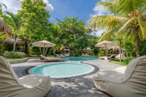 a swimming pool with two chairs and umbrellas at Village Bali in Uluwatu