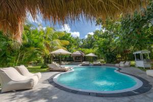 a swimming pool with chairs and umbrellas at Village Bali in Uluwatu
