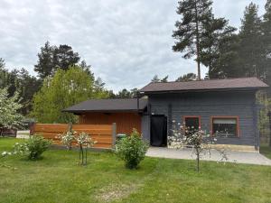 a small gray house with a bench in a yard at Cozy Forest Cabin in Kadaga