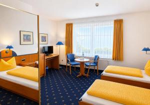 a hotel room with two beds and a desk and a table at Sporthotel Middelpunkt in Aurich