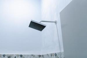 a shower head in a bathroom with a white shower curtain at Luchis HOME Ijen in Banyuwangi +42 photos