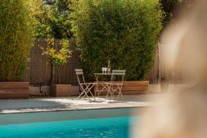 a cat sitting on a table in front of a pool at Le Cabanon de Val in Gassin