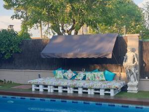 a bed sitting next to a pool with a statue at Espaciosa villa con piscina, ideal para relajarse en familia in Los Hueros