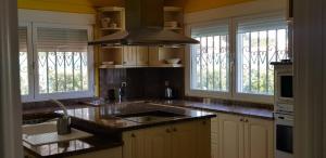 a kitchen with a sink and a stove and windows at Espaciosa villa con piscina, ideal para relajarse en familia in Los Hueros