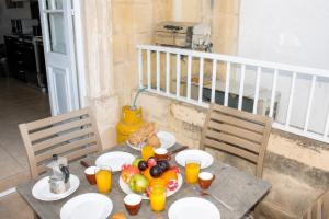 a table with plates of fruit and orange juice on it at Blue Harbour 2 bedroom Seafront Apartments with large terrace with spectacular sea views - by Getawaysmalta in St. Paul's Bay