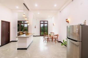 a kitchen with a refrigerator and a table with chairs at Ayurishi Villa in Hikkaduwa