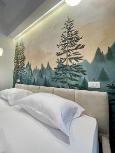 a bedroom with a painting of trees on the wall at Bora Hotel in Gjirokastër