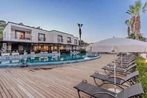 a pool with chairs and an umbrella next to a building at Mira Beach Resort Bodrum - All inclusive in Bodrum City