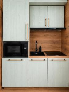 a kitchen with white cabinets and a black microwave at Apartmán 18 Lidická bouda in Pec pod Sněžkou