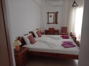 a bedroom with a bed with white sheets and red pillows at IASONAS APARTMENTS in Mastihari
