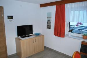 ein Wohnzimmer mit einem TV auf einem Schrank und einem Fenster in der Unterkunft Ferienwohnung Nuener in Grins