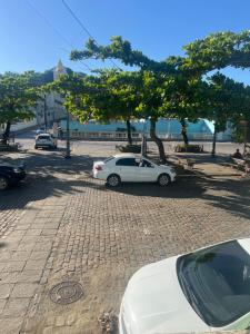 a white car parked next to a tree on a street at Pousada Oliveira in Cachoeira +3 photos