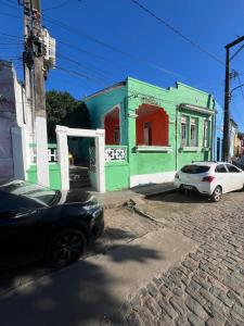 a green building with a car parked in front of it at Pousada Oliveira in Cachoeira