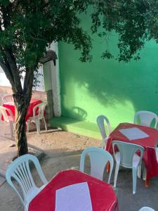 a red table with white chairs and a tree at Pousada Oliveira in Cachoeira
