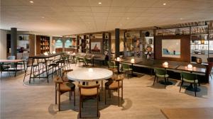 a restaurant with tables and chairs in a room at Postillion Hotel Breda Biesbosch in Raamsdonksveer