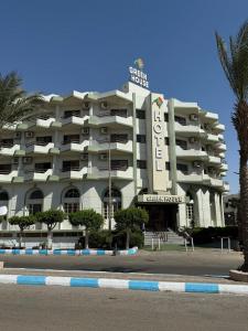 a large white building with a sign on top of it at Green House Hotel in As Suways