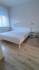 a white bed in a bedroom with a wooden floor at Regina Vendégház Miskolc in Miskolc