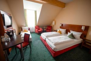 a hotel room with two beds and a table and chairs at Hotel Weisses Lamm in Veitshöchheim