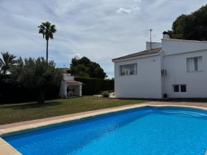 a villa with a swimming pool in front of a house at Acogedora casa con piscina in Lliria