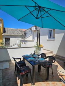 a table with chairs and a blue umbrella on a patio at Apartment Tičić in Povljana