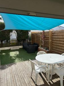 a patio with a table and chairs under a blue umbrella at À 100m de l ocean in Longeville-sur-Mer