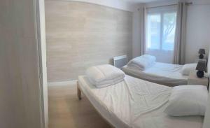 two twin beds in a room with a window at À 100m de l ocean in Longeville-sur-Mer +8 photos