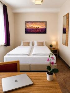 a bedroom with a bed and a table with a laptop at Hotel Pale Wolfsburg 24H Self Check-in in Wolfsburg