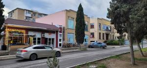 two cars driving down a city street with buildings at Ganja Apart in Ganja