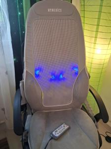 a remote control sitting in a computer chair with blue lights at Zöld otthon in Szeged
