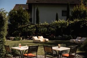 two tables and chairs in a yard with a couch at JOHAN - Rooms & Breakfast Merano in Marlengo