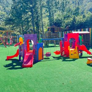 a playground with colorful play equipment on the grass at Loft no Refúgio do Sahy in Mangaratiba