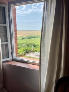 an open window with a view of a field at Borgo Belsedere - biofarm estate resort in Tuscany in Trequanda