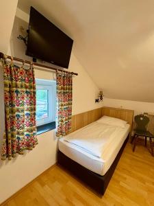 a bedroom with a bed and a flat screen tv at Pension Schwartzwirt in Neusiedl am Steinfelde