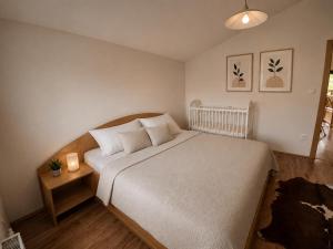 a bedroom with a large white bed and a night stand at Villa Sofia - dovolenkový dom pre 8 osôb in Batizovce