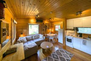 ein Wohnzimmer mit Sofa und Tisch und eine Küche in der Unterkunft Whispering Woods Cabin in Porvoo
