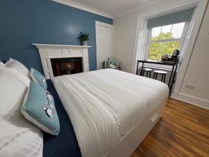 a bedroom with a large white bed and a fireplace at Nook and Scranny in Tarbert
