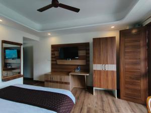 a bedroom with a bed and a flat screen tv at Hotel Summer Hill in Chail
