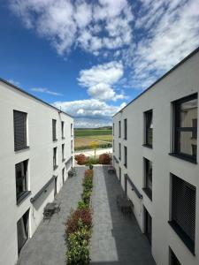 an alley between two white buildings with chairs at Intergroup Business & Design Hotel Ingolstadt in Kösching