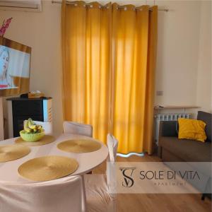 a living room with a table and chairs and a yellow curtain at Sole di Vita in Marina di Strongoli